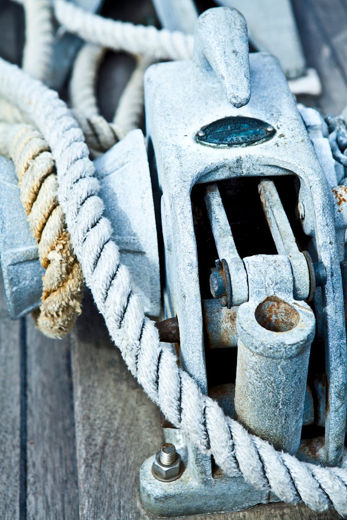 our-services-1 Detailed image of metal boat equipment with ropes on a wooden deck.